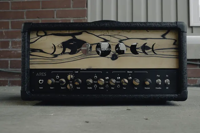 Tube amplifier head with moon-phase faceplate art on the loading dock
