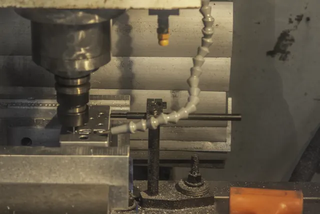 CNC mill cutting an aluminum pedal enclosure, with a coolant line on the part