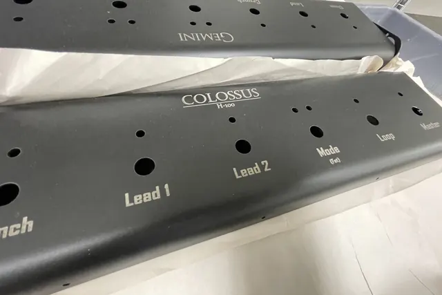Amplifier faceplates marked with control legends, stacked for assembly