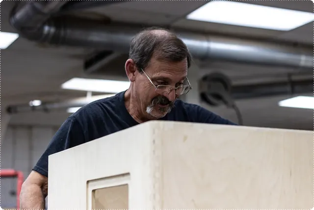 Craftsman finishing a birch speaker cabinet in the woodshop